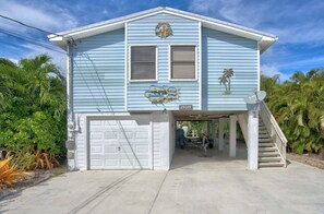 Een lichtblauwe woning met een garage, een overdekte veranda en een trap naar de ingang.