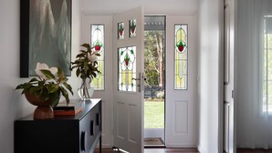 A hallway with a white door, a potted plant, and a painting on the wall.