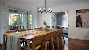 A dining area with a long wooden table, multiple chairs, and a chandelier.