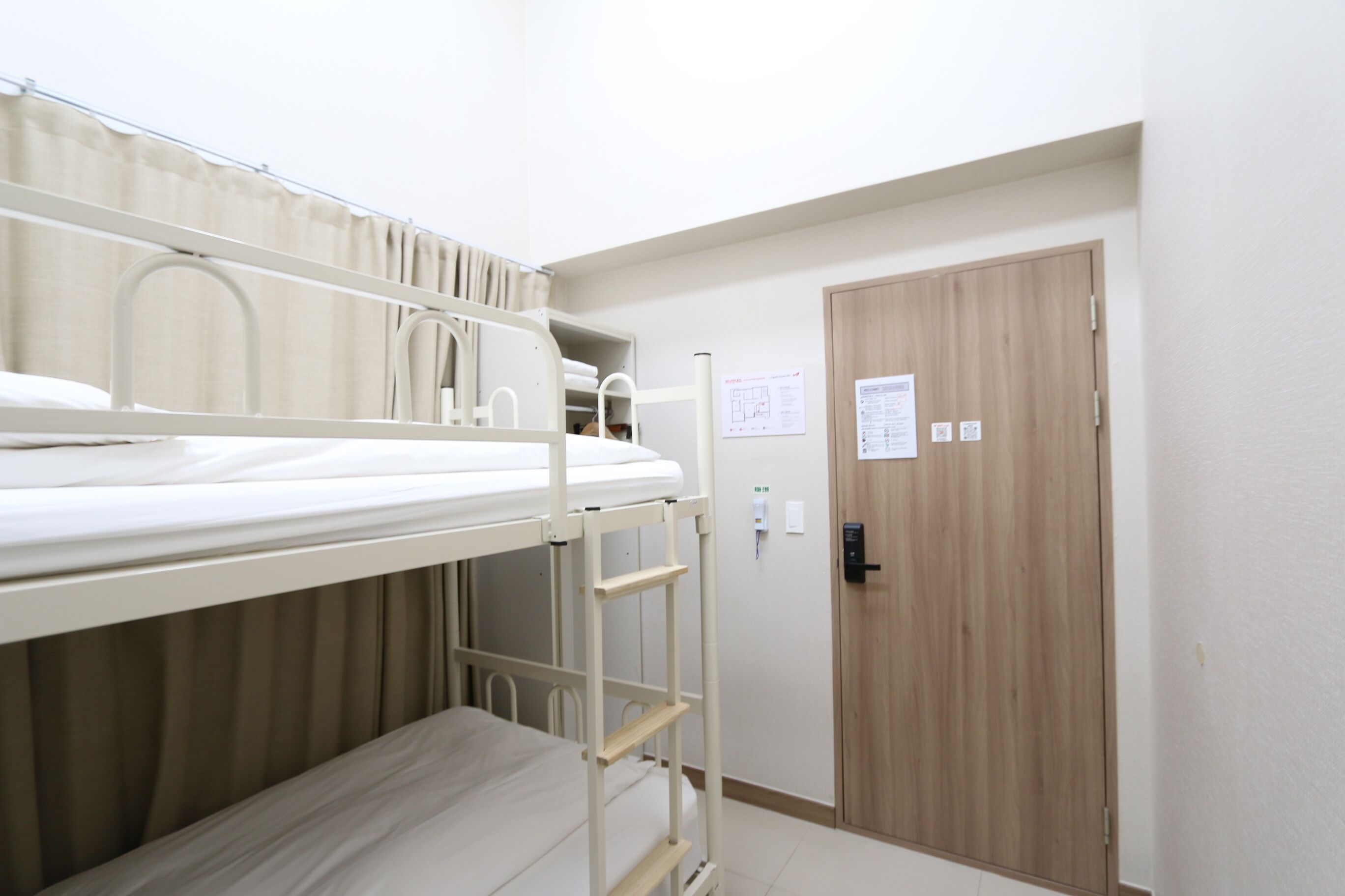 A bunk bed room with a wooden door and a white wall.