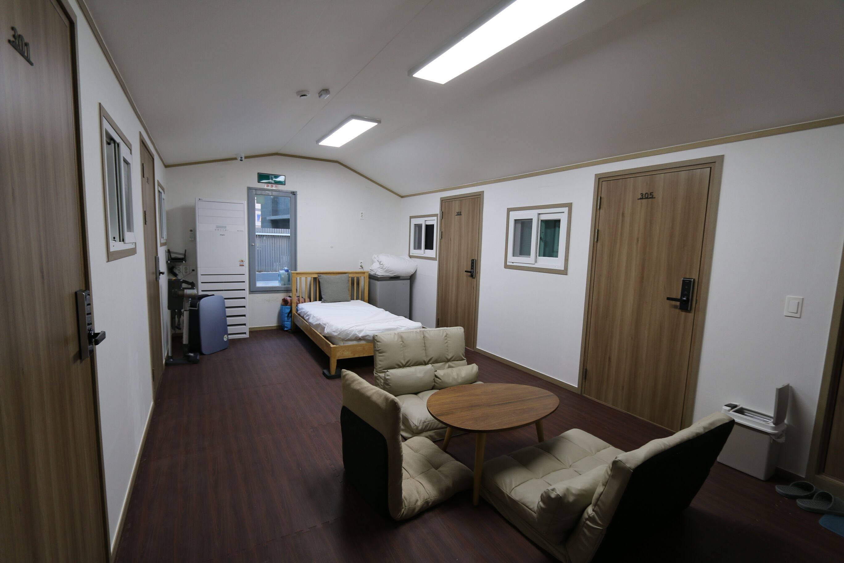 Una habitació amb llit, escriptori, cadira, taula petita i armari.