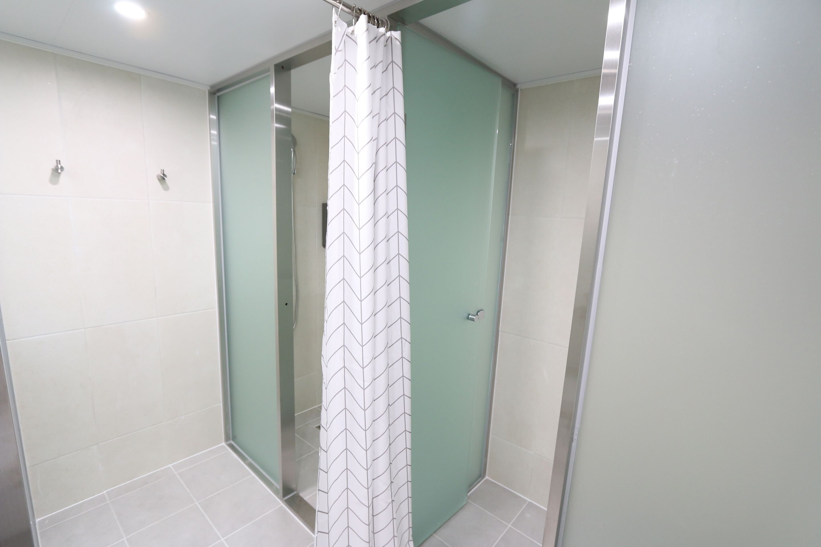 A modern bathroom with a shower area, a glass door, and a green accent wall.
