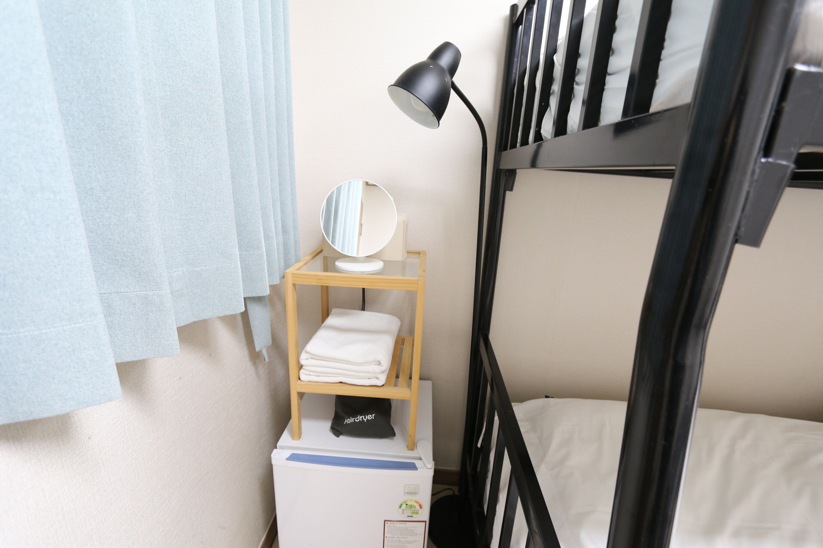 Ein Etagenbett mit Nachttisch, Lampe, Spiegel und einem Trockner.