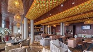 A spacious indoor area with high ceilings, large windows, and a variety of seating arrangements including tables and chairs. - MARLIN RESORT (Nyanyanu)