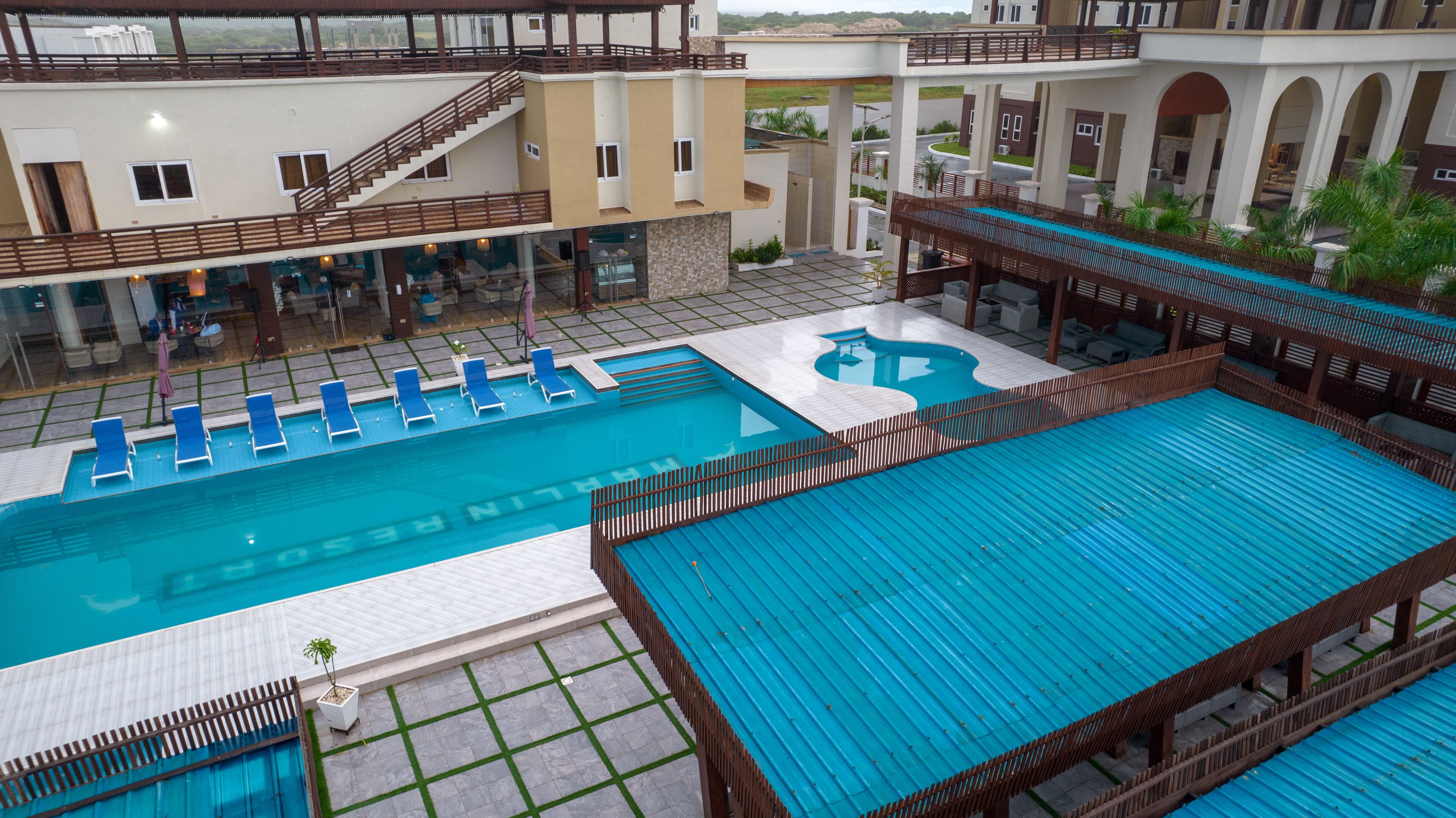 A swimming pool with blue water, surrounded by lounge chairs and a wooden deck.