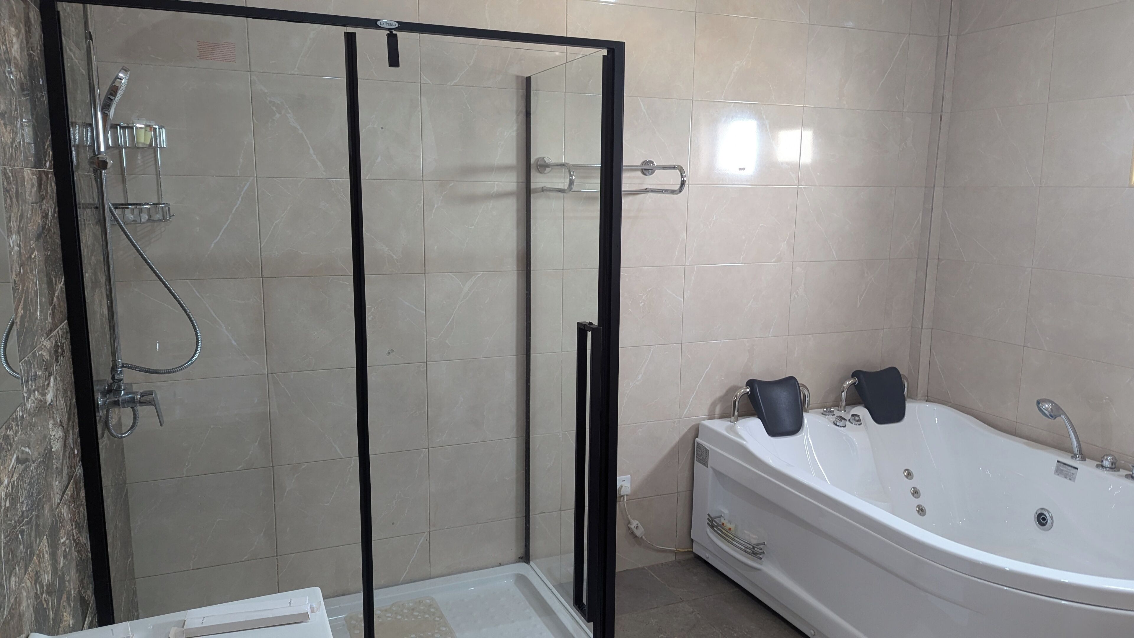 Un baño con ducha de vidrio, bañera blanca y piso de baldosas.