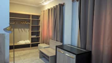 Spacious bedroom with wardrobe, bench, and bedside table.