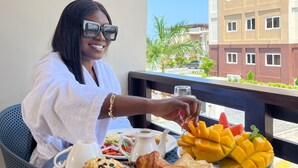A person seated at a table with a breakfast spread including croissants, muffins, toast, and fruit. - MARLIN RESORT (Nyanyanu)