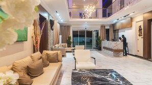 A spacious lobby with a marble coffee table, a reception desk, and a seating area with sofas and chairs. - MARLIN RESORT (Nyanyanu)