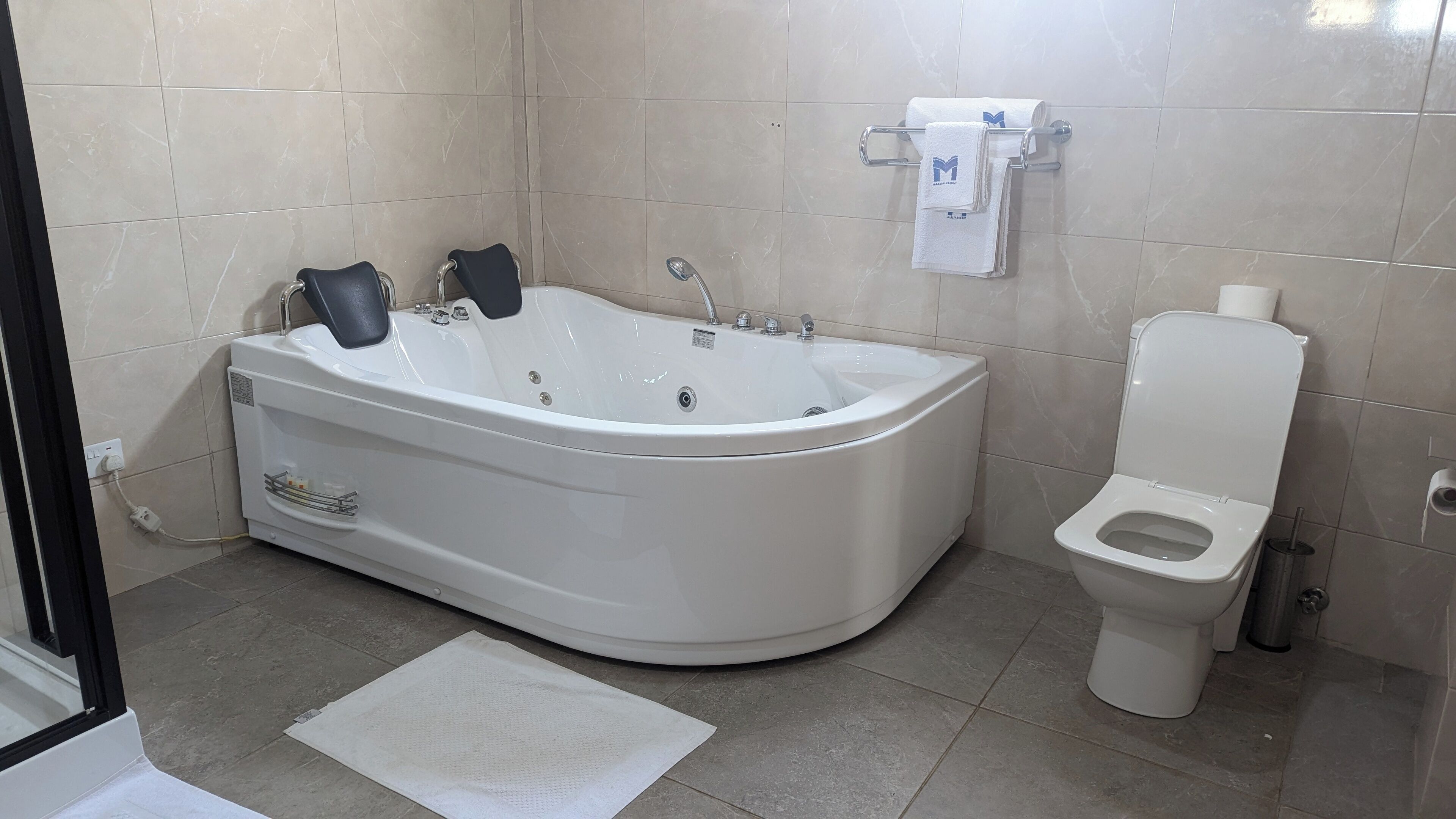 A bathroom with a bathtub, toilet, and a towel rack with towels.
