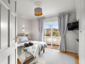 A bedroom with a bed, a television, and a view of the outdoors.