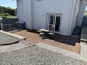 A patio area with a table and chairs, a wooden deck, and a gravel path. - An tSean Scoil, Clifden (Clifden)