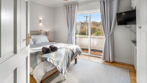 A bedroom with a bed, a TV, and a view of the outdoors. - An tSean Scoil, Clifden in the heart of clifden town (Clifden)