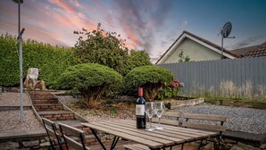 A wooden deck with picnic tables and benches, a bottle of wine, and two glasses on a table. - An tSean Scoil, Clifden in the heart of clifden town (Clifden)