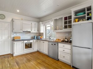 A kitchen with white cabinetry, a stainless steel refrigerator, and a wooden floor. - An tSean Scoil, Clifden (Clifden)