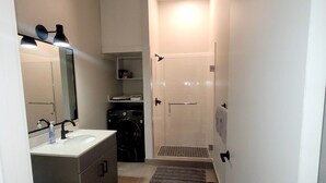 Une salle de bain compacte comprenant un lavabo, un miroir, des toilettes et une douche à l’italienne.