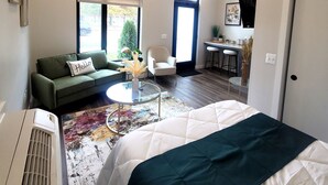 Une chambre moderne avec un grand lit, un canapé vert, une petite table ronde et un bureau avec une chaise.
