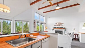 A modern kitchen with wooden countertops, a built-in dishwasher, and a large window overlooking a forest. - Saddleback - Rock Pond Condo 43 - ski in/out, pet friendly! (Rangeley)