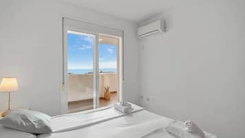Une chambre d’hôtel avec un lit, une lampe, une fenêtre donnant sur un paysage agréable et un appareil de climatisation.