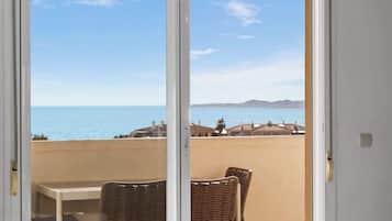 Un balcon avec vue sur la mer et les collines lointaines.