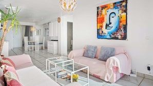 A modern living room with a pink sofa, a glass coffee table, and a large abstract painting on the wall. - Benalmadena over the sea by Costarentals - Ref 17 (Benalmádena)