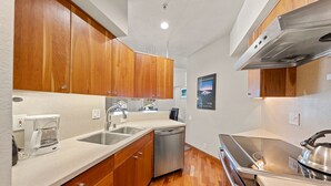 A modern kitchen with wooden cabinets, stainless steel appliances, and a built-in dishwasher. - 321 | Luxe Top Floor 1BD - A/C, Pool & Kitchen (Olympic Valley)