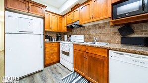 Una cocina con armarios de madera, refrigerador, estufa, microondas y lavavajillas.