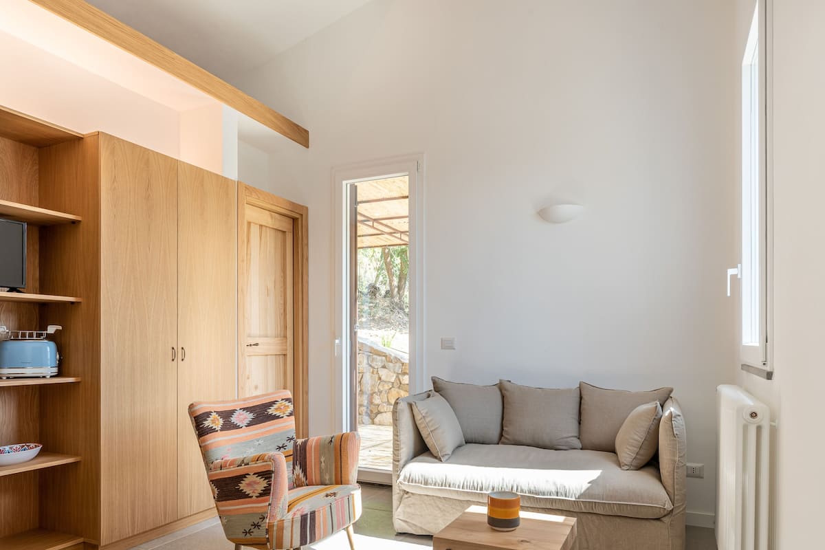 Un espace de vie compact comprenant un canapé, un fauteuil à motifs, un meuble en bois et une petite table.