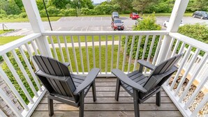 Eine HolzdTerrasse mit zwei Adirondack-Stühlen, die auf einen Parkplatz blicken.