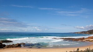 Ein Strand mit Felsen und brechenden Wellen.