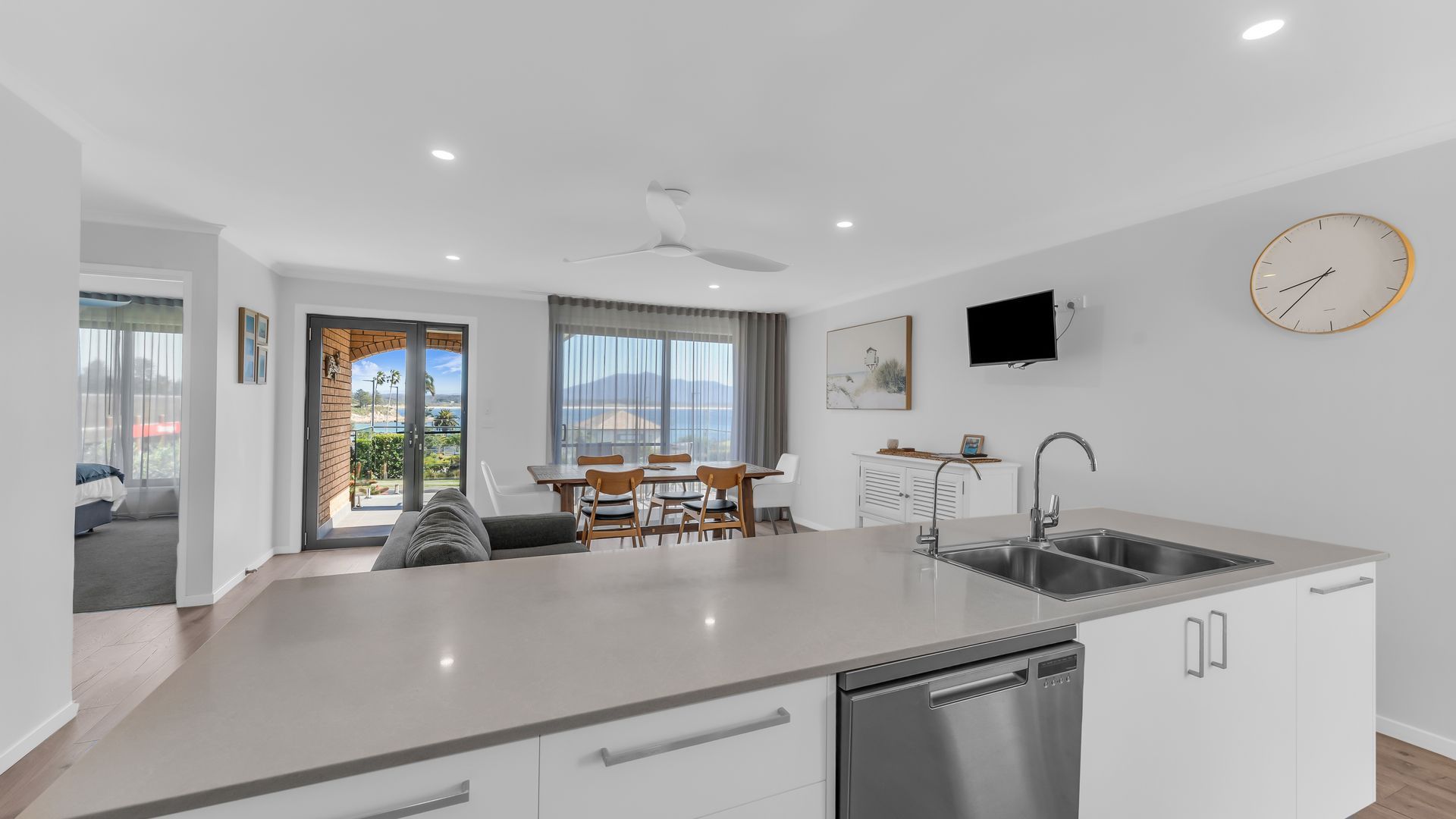 A modern kitchen with a built-in dishwasher, a dining area with a table and chairs, and a large window offering a view of the outdoors.