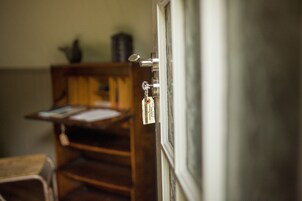 Una habitación con una silla de madera, una mesita y una ventana que da al exterior.
