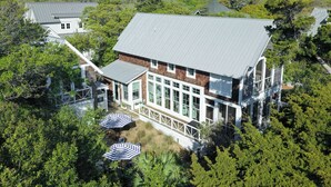 Une maison à deux étages dotée d’un grand balcon, entourée d’une végétation luxuriante.