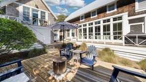 Une terrasse en bois avec des fauteuils Adirondack, un foyer en métal et un espace patio couvert.