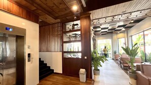 A hotel lobby with a wooden staircase, a reception desk, and a seating area with potted plants. - Le Vert Angkor Hotel  (Siem Reap)
