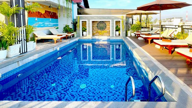 A rooftop pool with lounge chairs and umbrellas, surrounded by potted plants and a mural. - Le Vert Angkor Hotel  (Siem Reap)