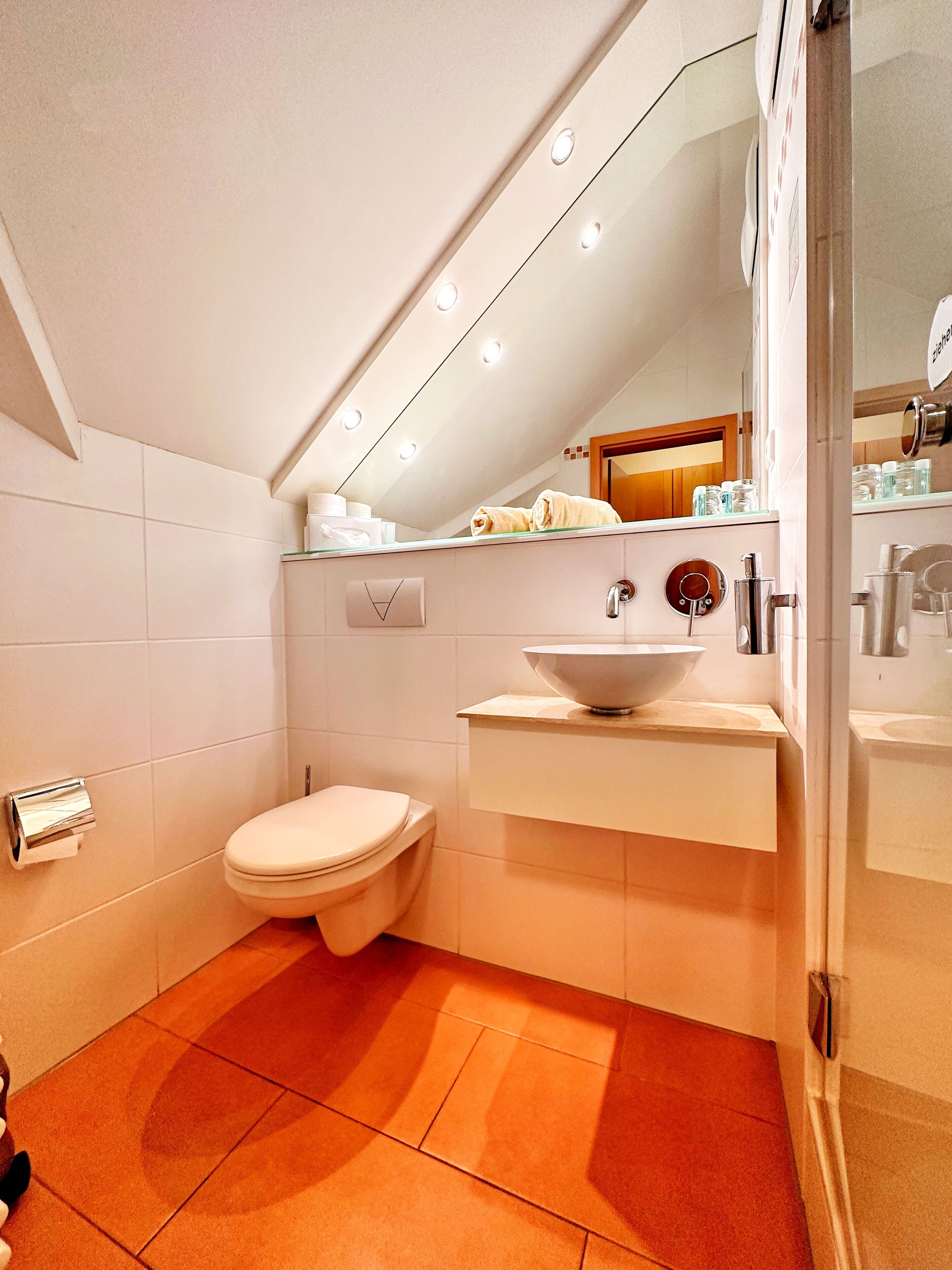 Ein modernes Badezimmer mit Toilette, Waschbecken und einem Spiegel darüber.