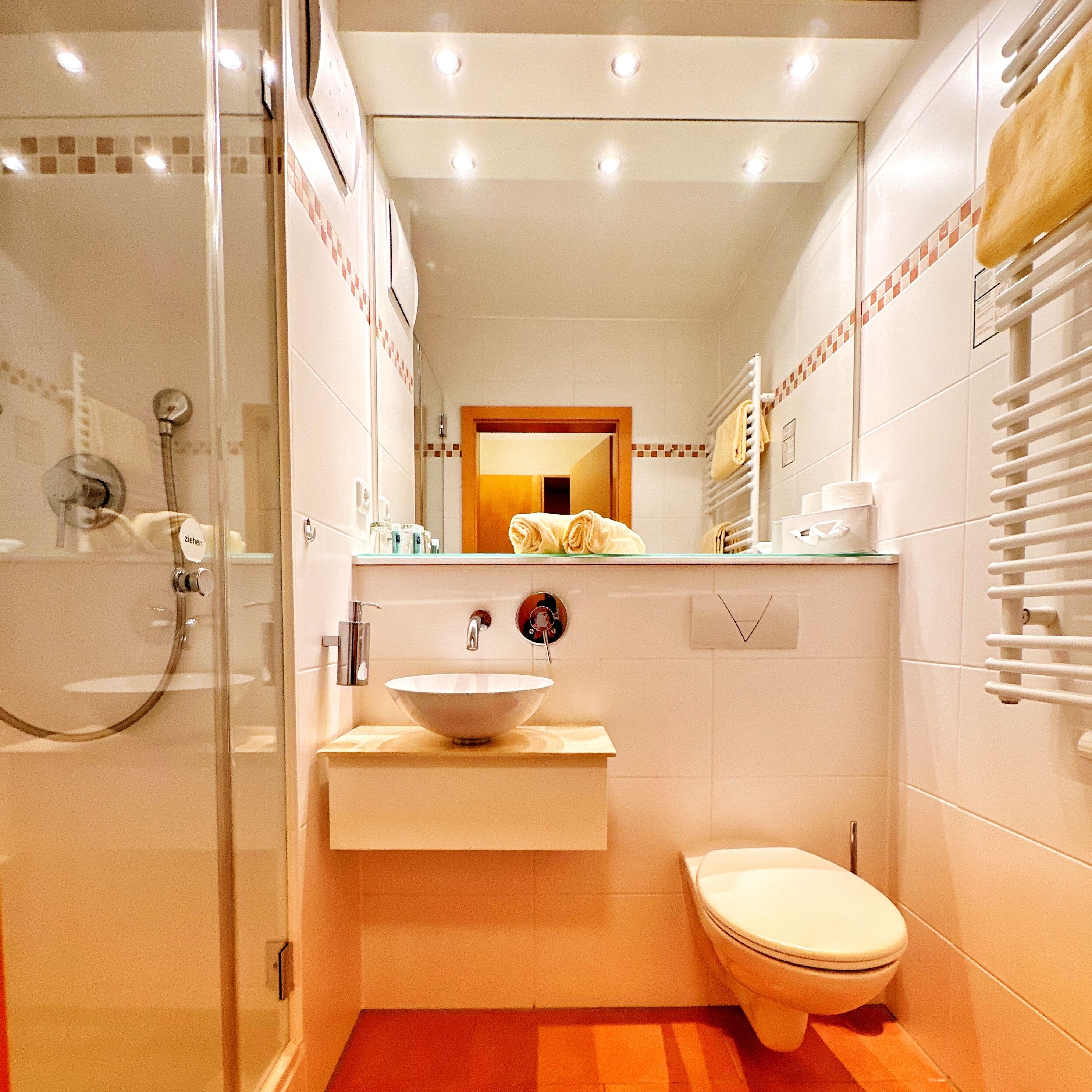 Ein kleines Badezimmer mit Duschkabine, Waschbecken mit Spiegel und Toilette.