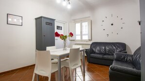 A dining area with a table and chairs, a grey cabinet, and a black leather sofa. - B&B il vagello (Florence)