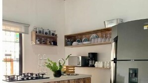 A kitchen with a wooden island, stainless steel appliances, and shelves with dishes.