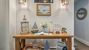 A reception desk with a sign reading "Lighthouse Landing," a framed painting of a lighthouse, and a vintage telephone. - Beautiful Inn, Lighthouse Landing. Sleeps 18-20 (Ogunquit)