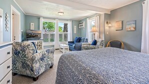 A bedroom with a bed, a sofa, a chair, and a desk. There are windows with curtains, a ceiling light, and wall art. - Beautiful Inn, Lighthouse Landing. Sleeps 18-20 (Ogunquit)