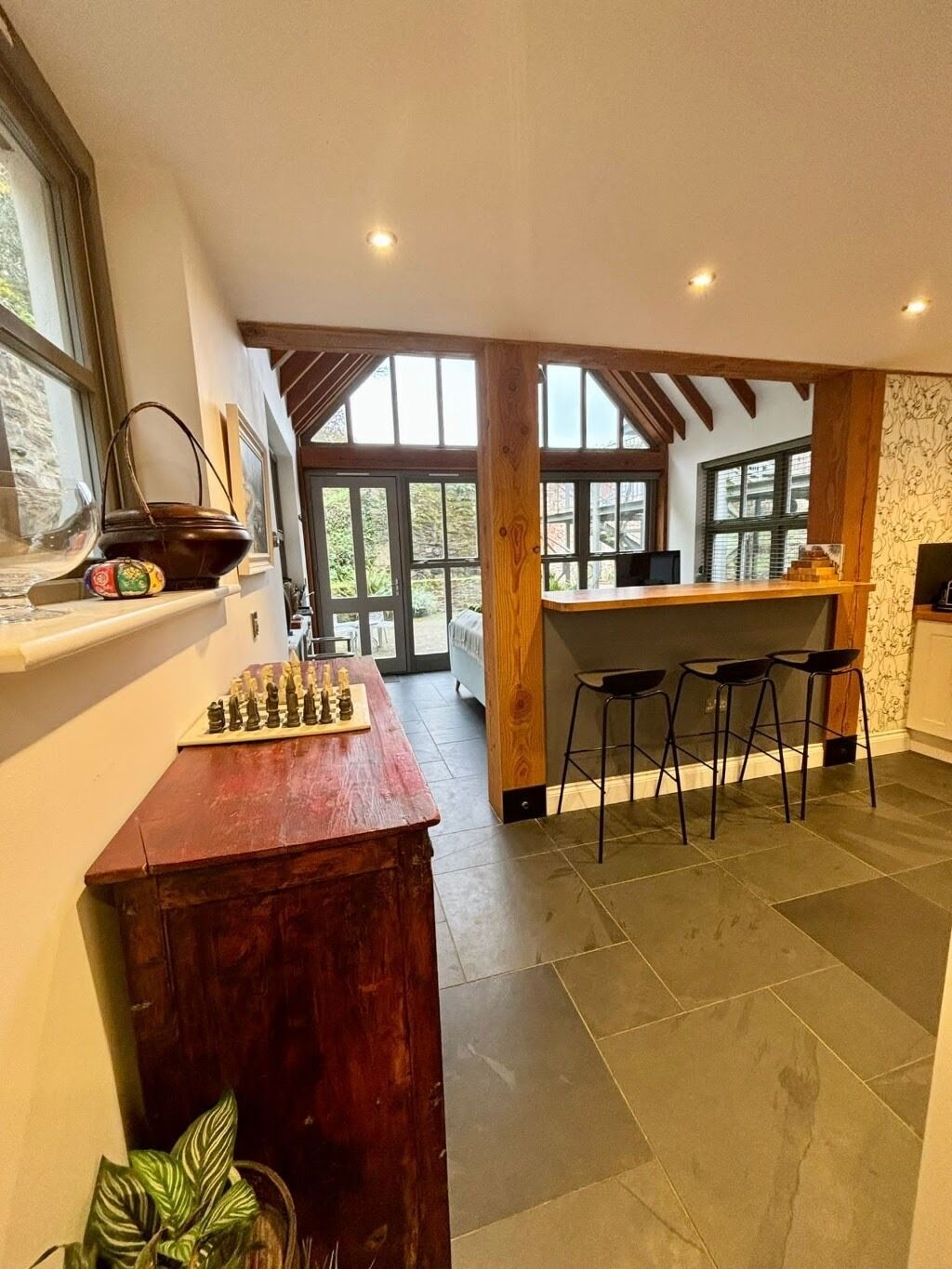 Een ruime keuken met een houten bar, een schaakbord en een groot raam dat voor natuurlijk licht zorgt.