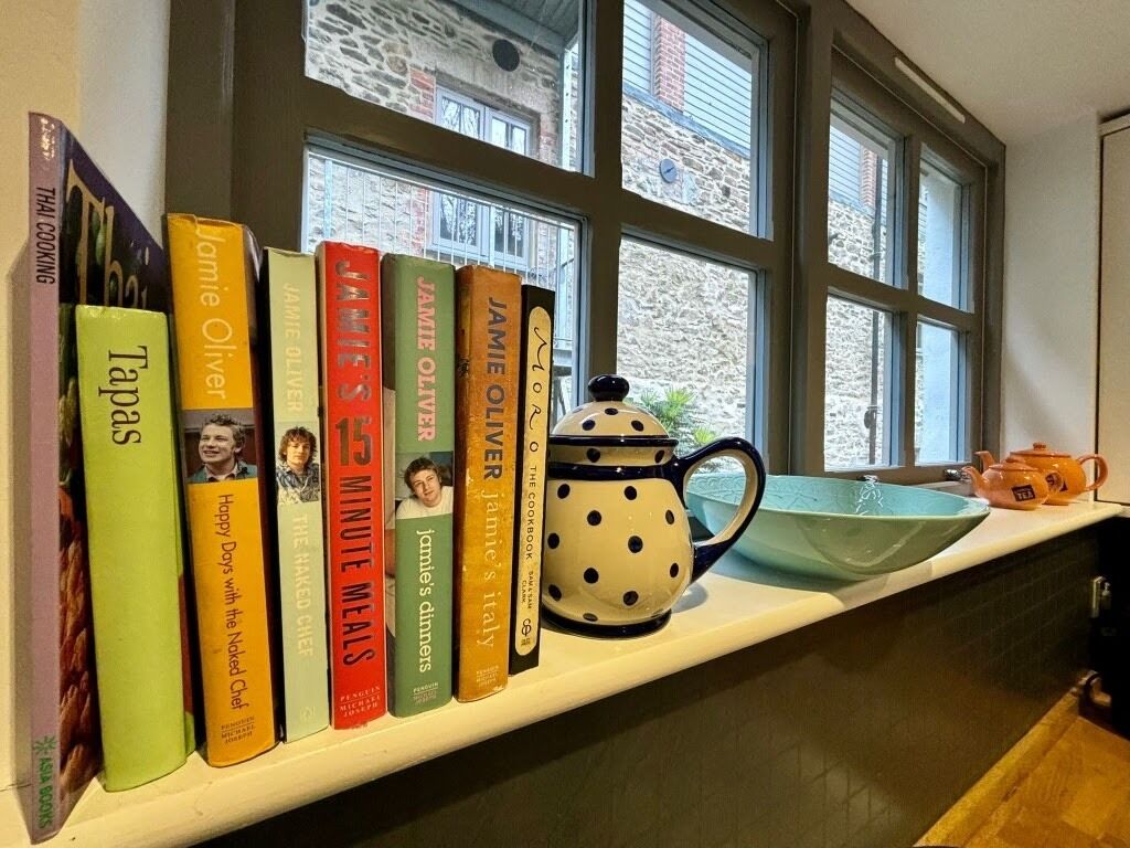 A shelf with books and a teapot.