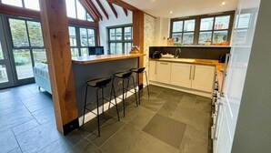 Une cuisine moderne avec un coin bar, de grandes fenêtres et un sol carrelé en pierre.