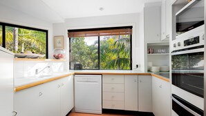 Una cucina moderna con mobili bianchi, lavastoviglie e una finestra vista su piante.
