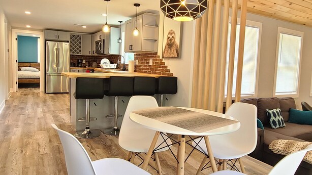 A modern kitchen with a central island, white chairs, and a hanging light fixture. - Fully remodeled house in perfect location (Irons)