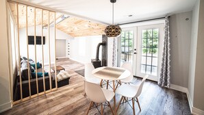 A modern living room with a wooden ceiling, a dining table with chairs, and a large window with curtains. - Fully remodeled house in perfect location (Irons)