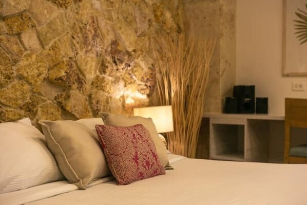 Experience a cozy retreat with a rustic stone wall, plush bed, and comfortable seating area.