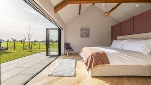 A bedroom with a large bed, a view of the outdoors, and a door leading to a balcony.